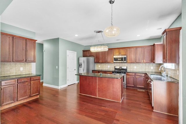 kitchen featuring appliances with stainless steel finishes, a sink, decorative backsplash, dark wood-style floors, and a chandelier
