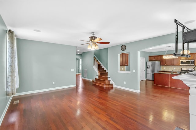unfurnished living room with ceiling fan, dark wood finished floors, and baseboards