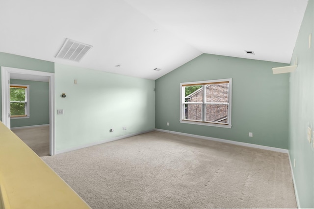 carpeted spare room with healthy amount of natural light, vaulted ceiling, and baseboards