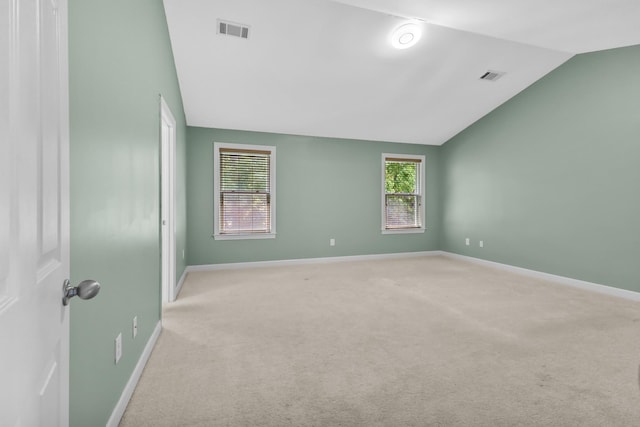unfurnished room with vaulted ceiling, light carpet, and baseboards