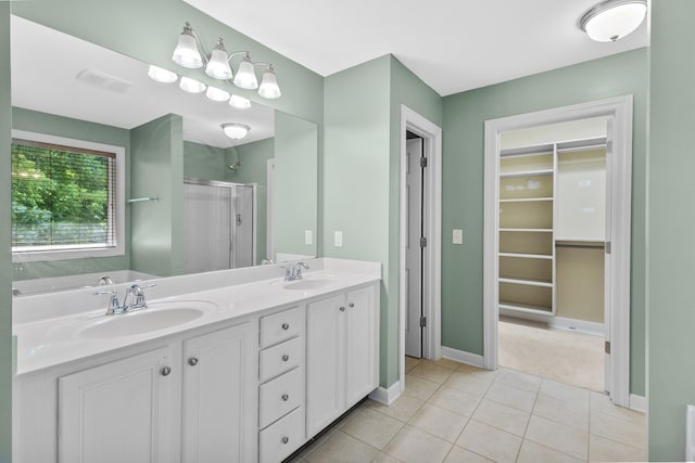 full bathroom with a shower stall, a spacious closet, baseboards, tile patterned flooring, and double vanity