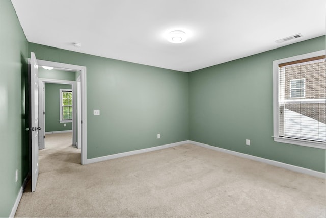 empty room featuring light colored carpet and baseboards