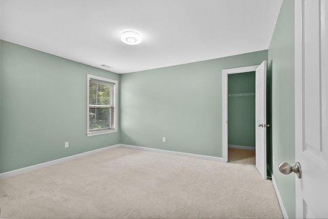 unfurnished bedroom with carpet flooring, a spacious closet, baseboards, and a closet