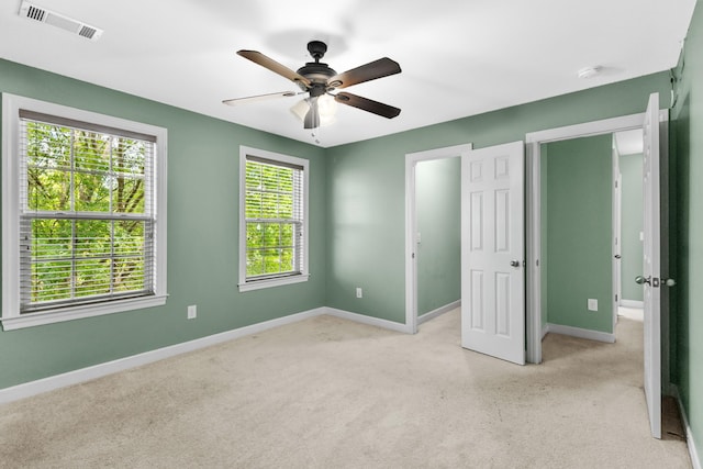 unfurnished bedroom featuring light carpet, baseboards, and a ceiling fan