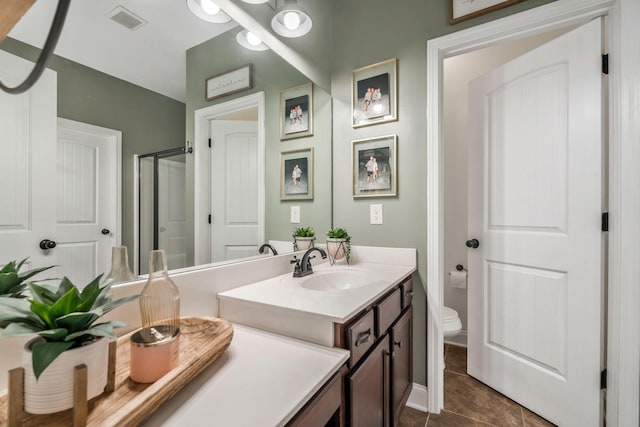 full bath featuring tile patterned floors, vanity, a shower with shower door, toilet, and visible vents