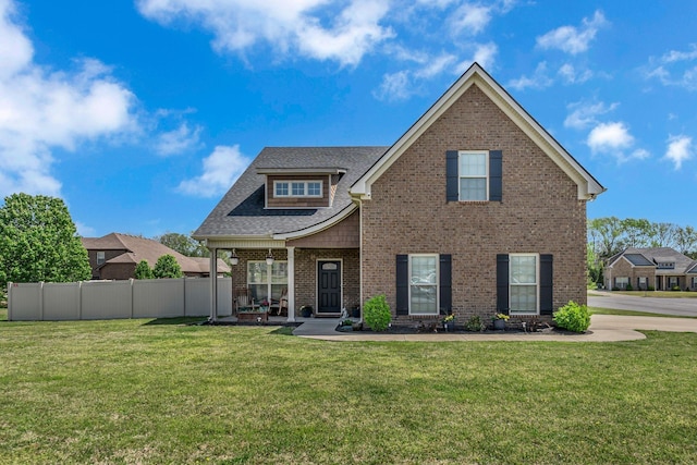 craftsman-style home featuring brick siding, a front lawn, fence, and a shingled roof