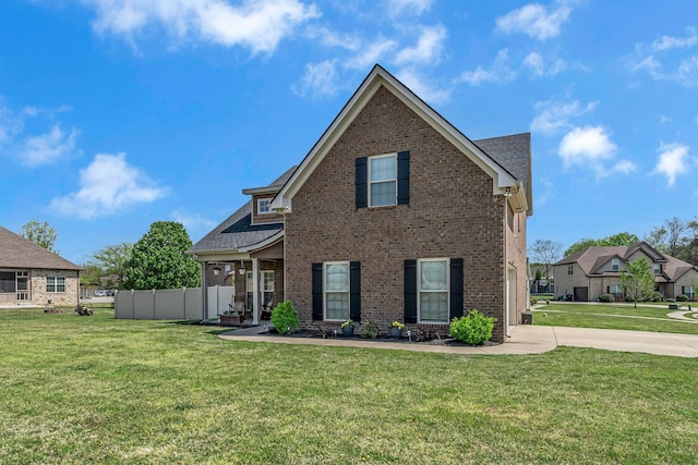 traditional home with roof with shingles, a front lawn, concrete driveway, fence, and brick siding