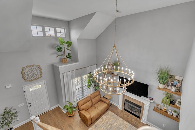 living area with a tile fireplace, a notable chandelier, wood finished floors, and plenty of natural light