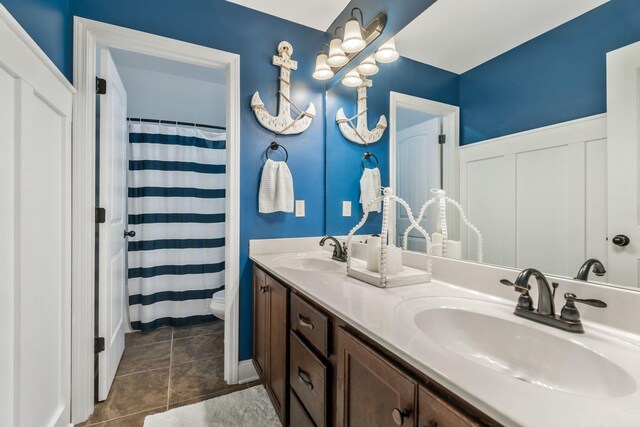 full bathroom featuring a shower with curtain, double vanity, toilet, and a sink