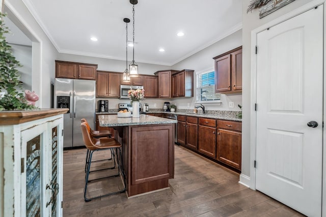 kitchen featuring dark wood-style floors, ornamental molding, light stone countertops, a kitchen island, and appliances with stainless steel finishes