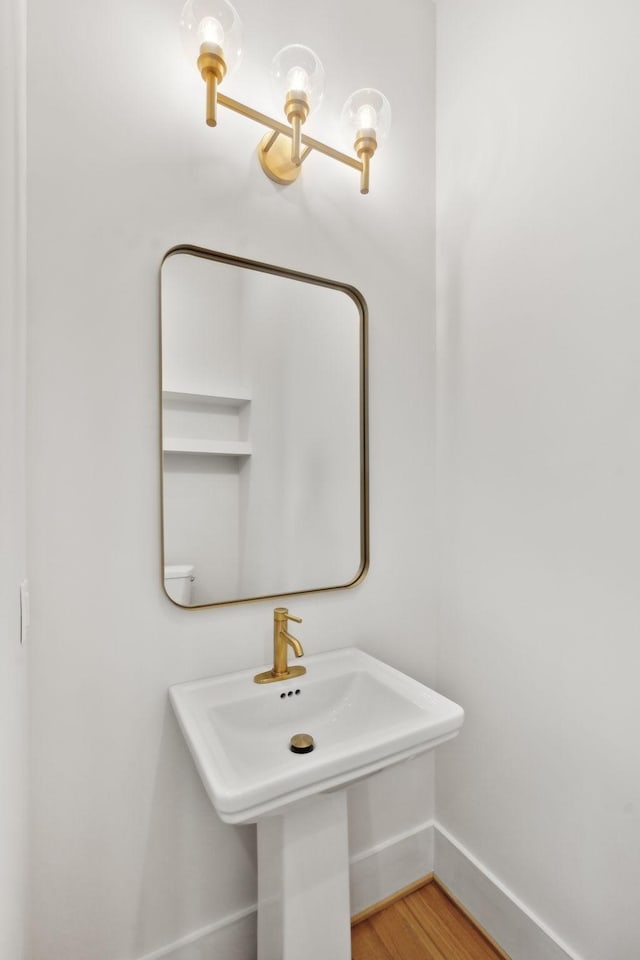 bathroom with wood finished floors, baseboards, and a sink