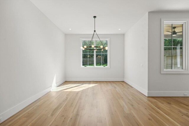unfurnished dining area featuring a chandelier, light wood finished floors, and baseboards