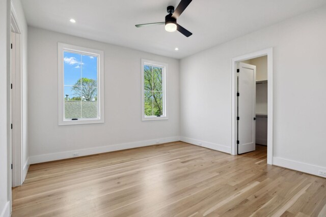 unfurnished bedroom with light wood-style flooring, baseboards, a closet, and a walk in closet