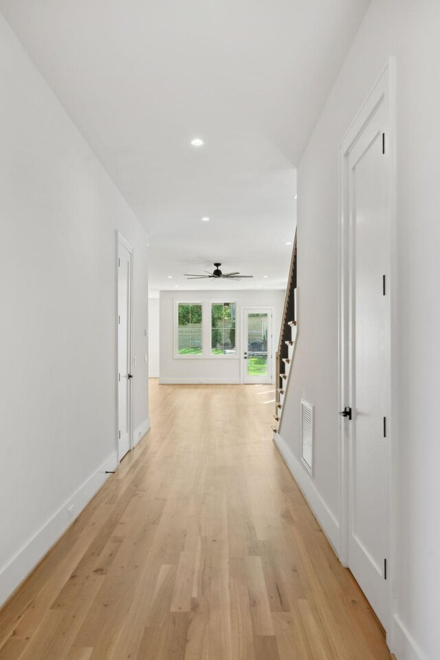 hallway with stairs, light wood finished floors, baseboards, visible vents, and recessed lighting