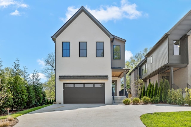 contemporary house featuring an attached garage, driveway, and stucco siding