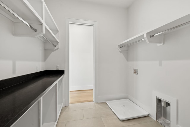 clothes washing area featuring baseboards, hookup for a washing machine, laundry area, and light tile patterned floors