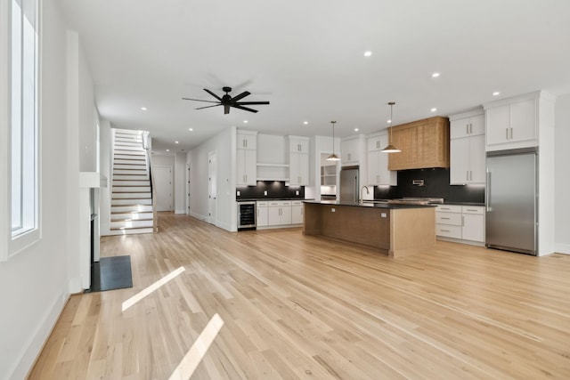 kitchen with a sink, dark countertops, recessed lighting, built in refrigerator, and beverage cooler