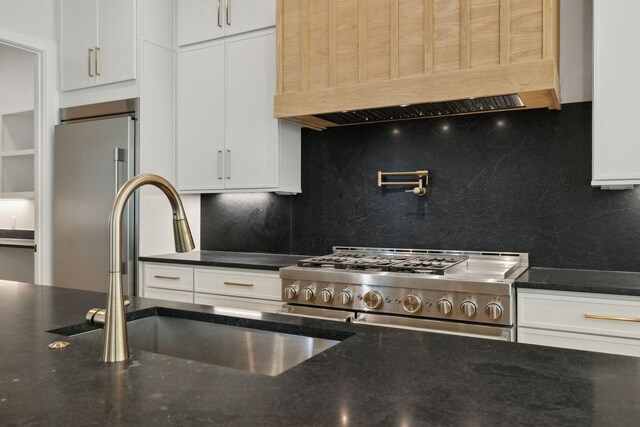 kitchen with custom exhaust hood, tasteful backsplash, a sink, high end appliances, and white cabinets