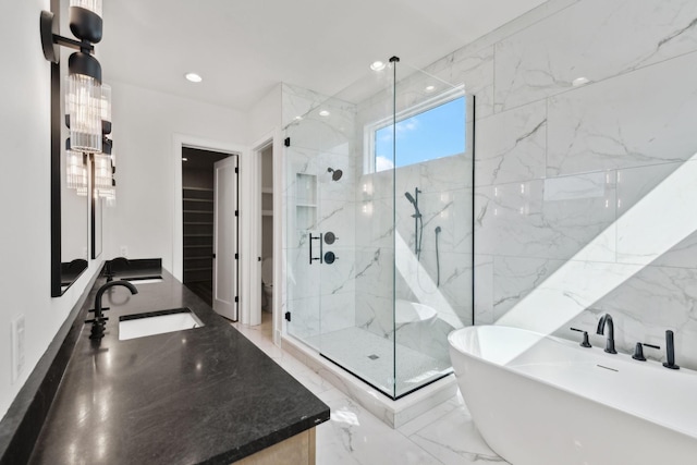full bathroom featuring a stall shower, recessed lighting, marble finish floor, a freestanding tub, and vanity