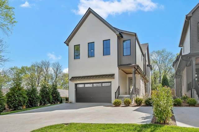 view of front facade with a standing seam roof, metal roof, concrete driveway, a garage, and stucco siding