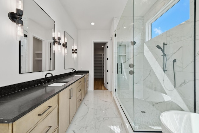 bathroom featuring marble finish floor, a sink, a shower stall, and a walk in closet