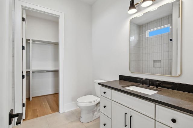 bathroom with tile patterned floors, a spacious closet, vanity, walk in shower, and toilet