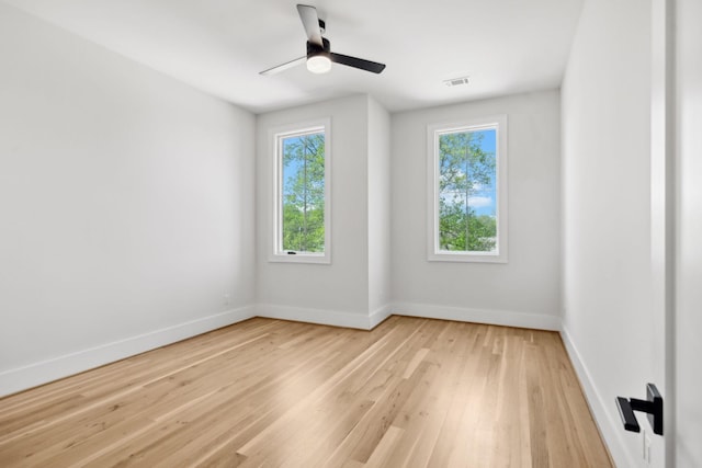 spare room with baseboards, visible vents, light wood-style floors, and ceiling fan