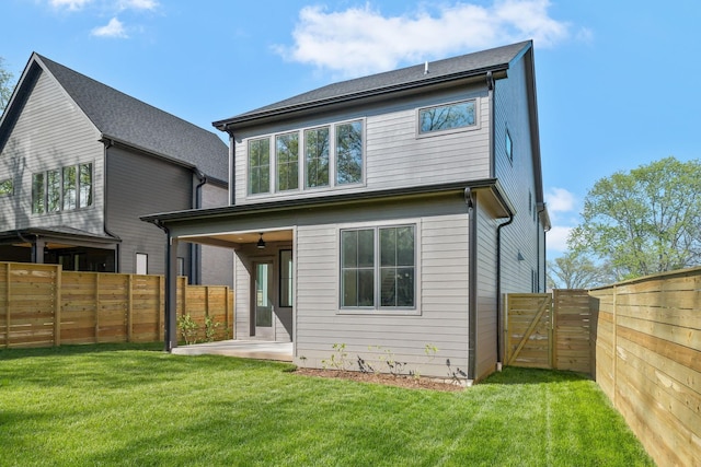 rear view of property featuring a gate, a lawn, a patio, and a fenced backyard