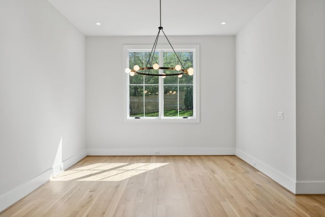 unfurnished dining area featuring baseboards, wood finished floors, and a chandelier