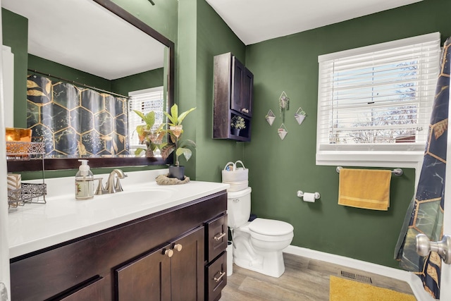 full bath featuring wood finished floors, visible vents, toilet, vanity, and baseboards