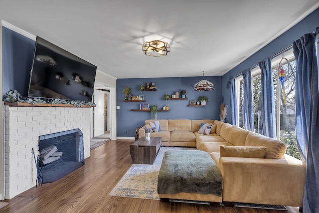 living room featuring wood finished floors, a fireplace, and ornamental molding
