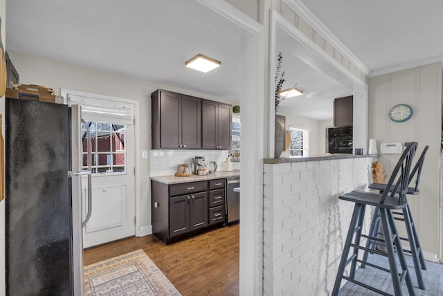 kitchen with a wealth of natural light, dark brown cabinetry, wood finished floors, and stainless steel appliances