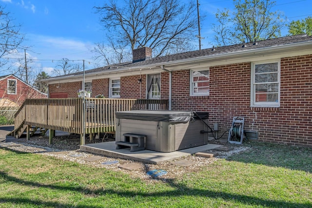 back of house featuring brick siding, a yard, a hot tub, and a wooden deck