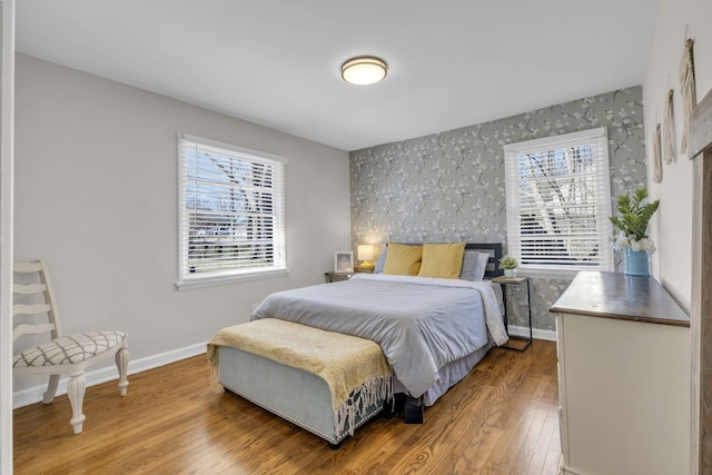 bedroom featuring baseboards, wood finished floors, and wallpapered walls