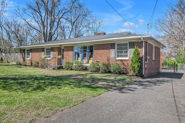 ranch-style house with a chimney, a front lawn, brick siding, and fence