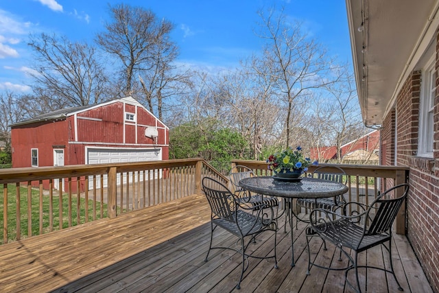 wooden terrace featuring an outbuilding, outdoor dining space, and a detached garage