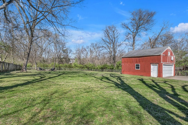 view of yard featuring fence, an outbuilding, a barn, and a detached garage