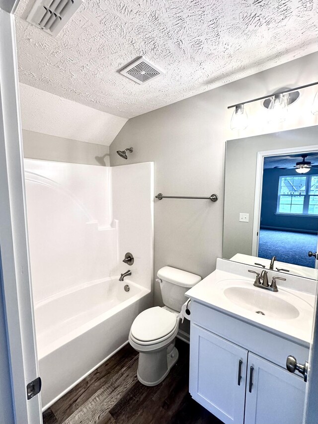 bathroom with wood finished floors, a textured ceiling, vanity, toilet, and visible vents