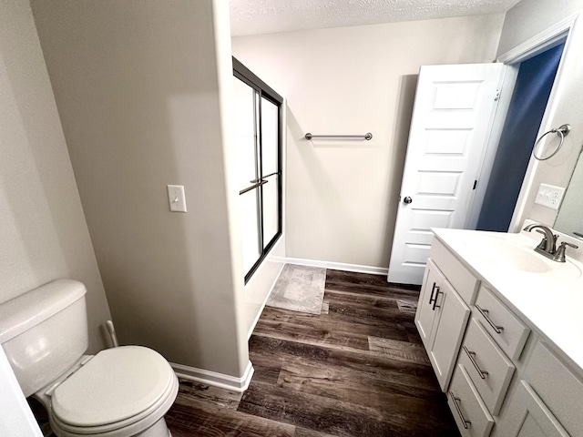 bathroom featuring baseboards, wood finished floors, vanity, and toilet