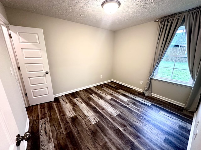 empty room with baseboards, a textured ceiling, and dark wood-style floors