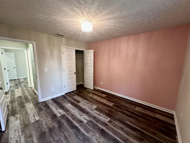 unfurnished bedroom with baseboards, dark wood-type flooring, and visible vents