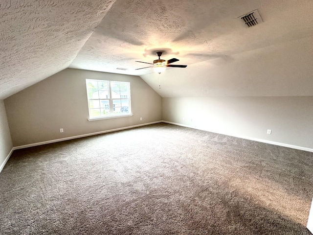 bonus room with carpet, visible vents, and a textured ceiling
