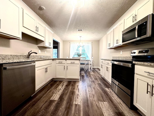 kitchen featuring a textured ceiling, appliances with stainless steel finishes, white cabinets, dark wood-style flooring, and visible vents