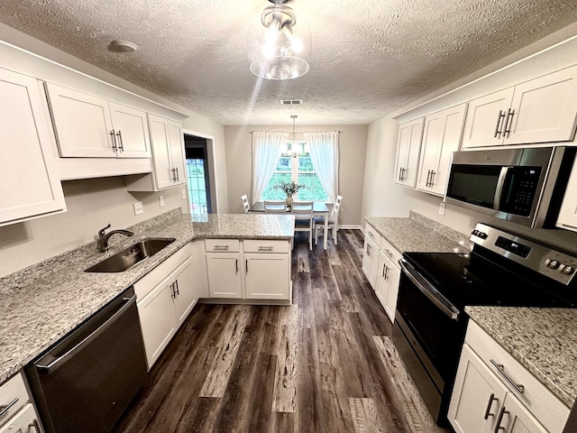 kitchen featuring a textured ceiling, a sink, stainless steel appliances, white cabinets, and dark wood-style flooring