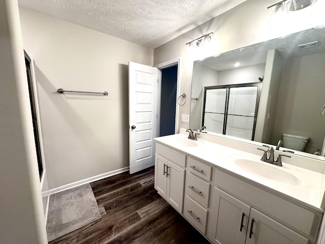 full bathroom featuring a shower stall, wood finished floors, toilet, and a sink