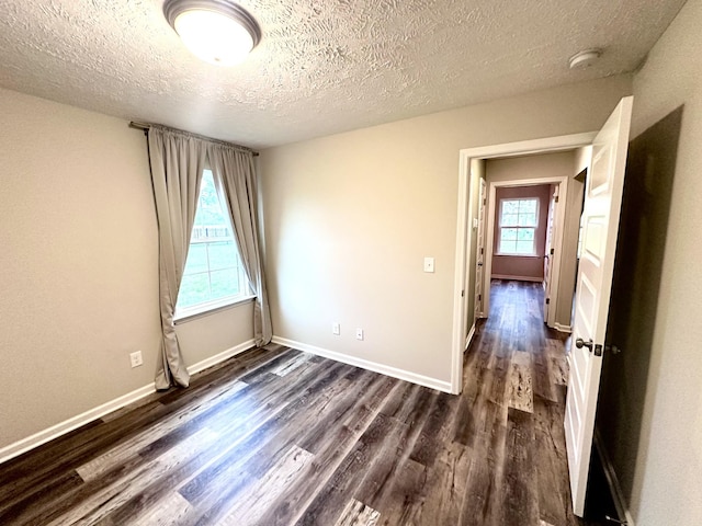 unfurnished room featuring dark wood finished floors, baseboards, and a textured ceiling