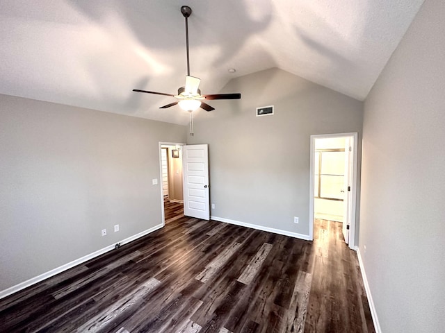 unfurnished bedroom with baseboards, vaulted ceiling, visible vents, and dark wood finished floors