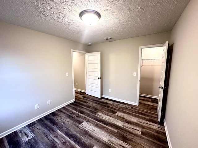 unfurnished bedroom featuring baseboards, visible vents, dark wood-type flooring, and a textured ceiling