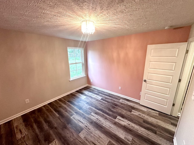 empty room with dark wood-type flooring, a textured ceiling, and baseboards