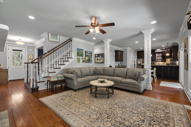 living area with ornate columns, ceiling fan, crown molding, and dark wood-style flooring